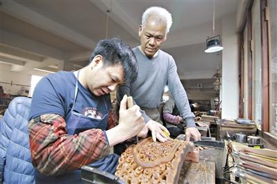 中國僑網(wǎng)胡敏強(qiáng)(右)在指導(dǎo)年輕人雕刻紅木。